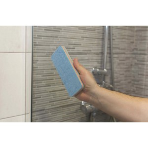 Mano che tiene l'attrezzo per la pulizia t.b.t. davanti alla parete della doccia piastrellata.