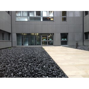 Ciottoli/granulati decorativi neri come copertura per aiuole davanti all'edificio.