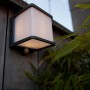Lampada da parete solare a LED Lutec Doblo color antracite con sensore di movimento su parete in legno.