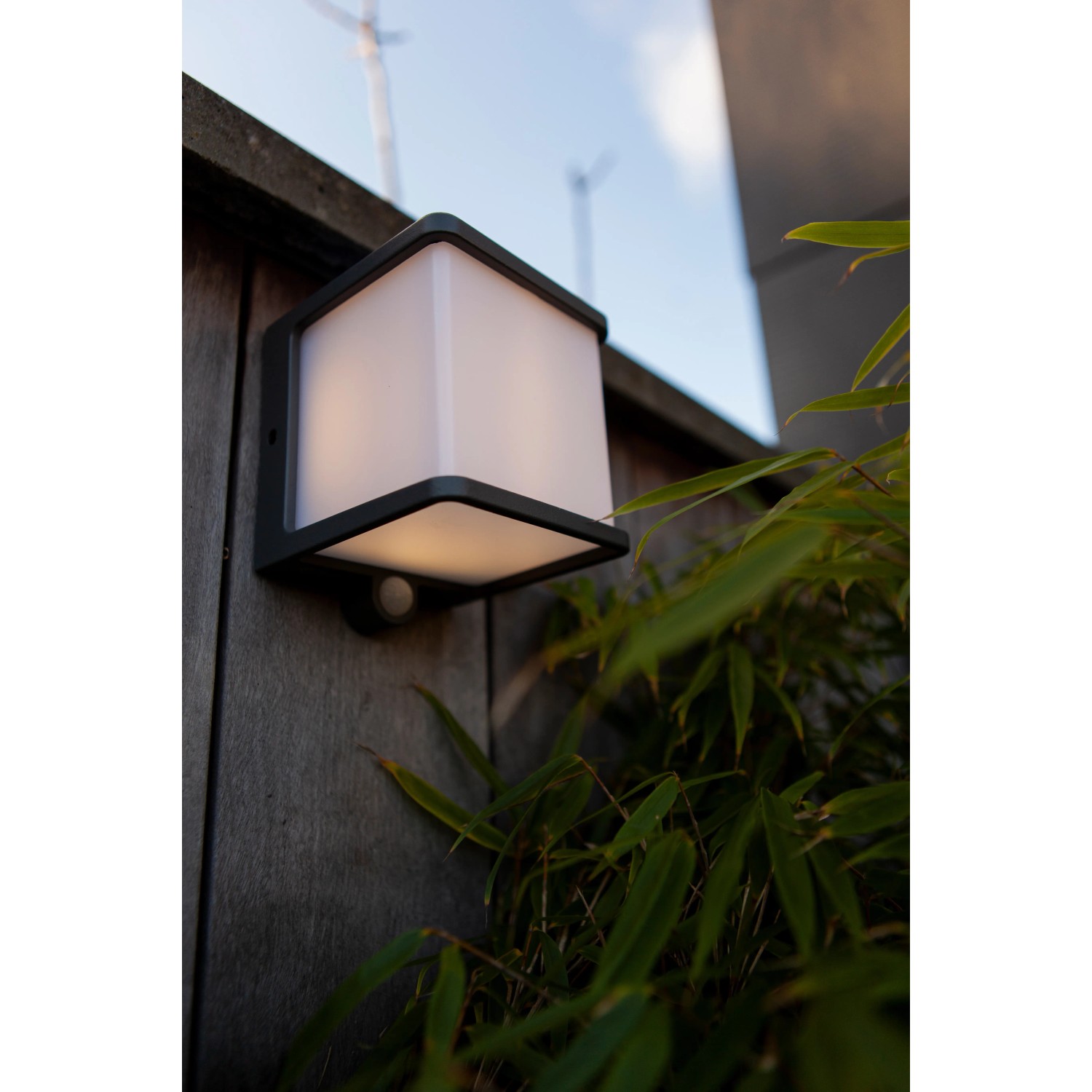 Lampada da parete solare a LED Lutec Doblo color antracite con sensore di movimento su parete in legno.