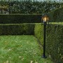 Lanterna da giardino t.b.t. nera su prato davanti a siepe verde.