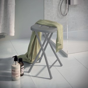 Sgabello da bagno pieghevole grigio con asciugamano in bagno.
