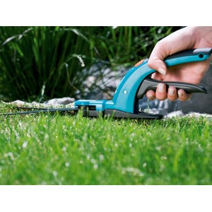Cesoie per erba Gardena Comfort in azione: mano taglia con precisione il bordo del prato. Cesoie da giardino con manico blu e nero.