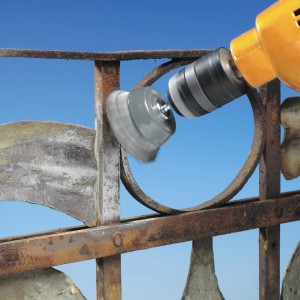 Spazzola a tazza LUX in uso su un trapano per rimuovere la ruggine da una recinzione metallica.