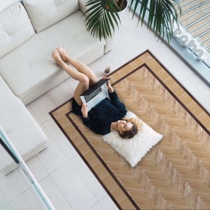 Donna sdraiata su tappeto moderno a spina di pesce con laptop.