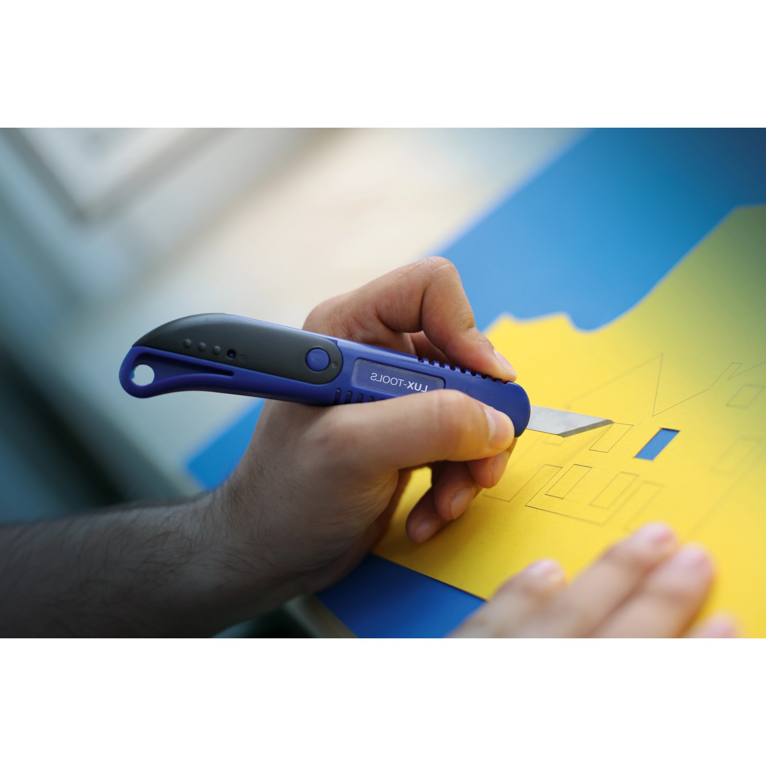 Taglierino di precisione LUX Classic taglia carta gialla. Cutter blu e nero in uso.