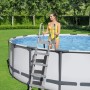 Scala grigia per piscina su piscina fuori terra con donna in costume giallo. Scalette per piscina.