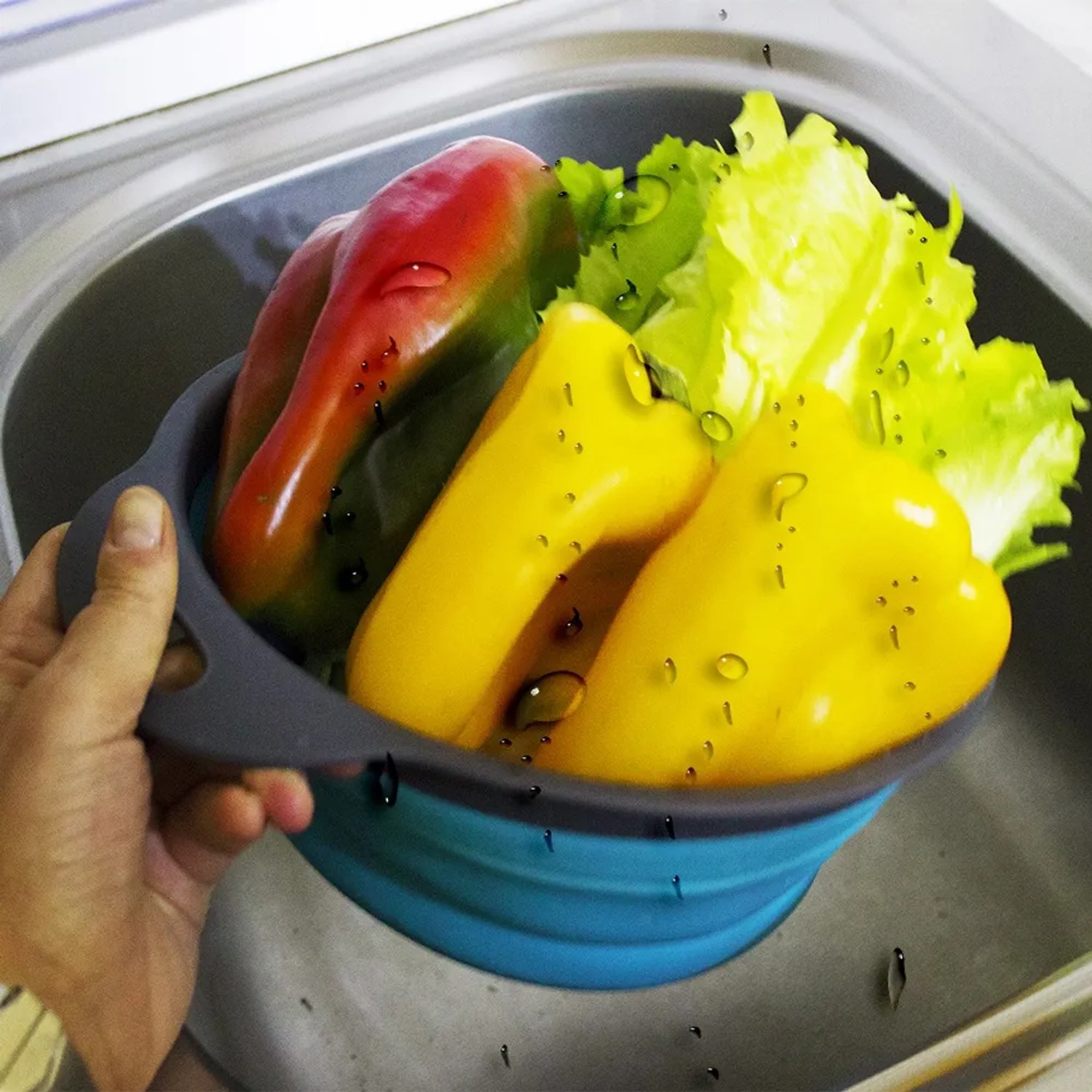 Verdure in scolapasta blu. Utensile da cucina per insalata e peperoni.