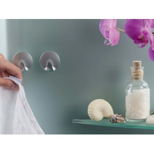 Due ganci adesivi t.b.t. argentati su una parete con un asciugamano appeso a uno.