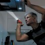 Uomo ispeziona cappa aspirante con torcia t.b.t. rossa.