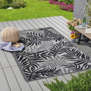 Tappeto da esterno t.b.t. con motivo a foglie di palma nere su terrazza.