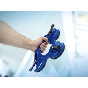 Mano che tiene un sollevatore a ventosa LUX Saugheber Classic 3-fold blu da 80 kg su un vetro.