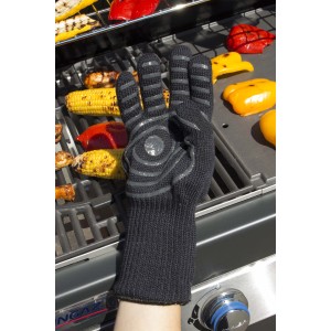 Guanto da barbecue nero con protezione termica davanti a griglia con verdure.