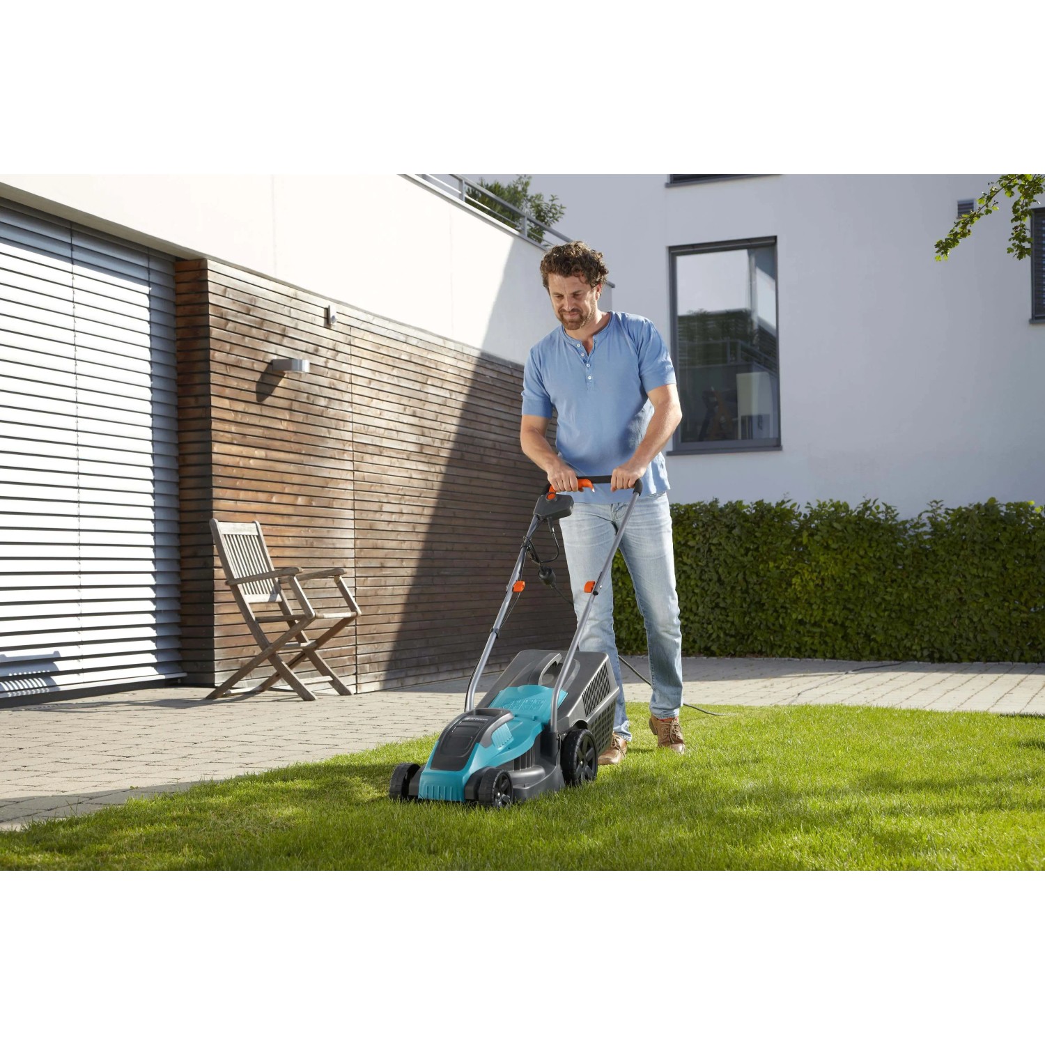 Uomo taglia l'erba con tosaerba elettrico blu e nero. Tosaerba della categoria t.b.t.