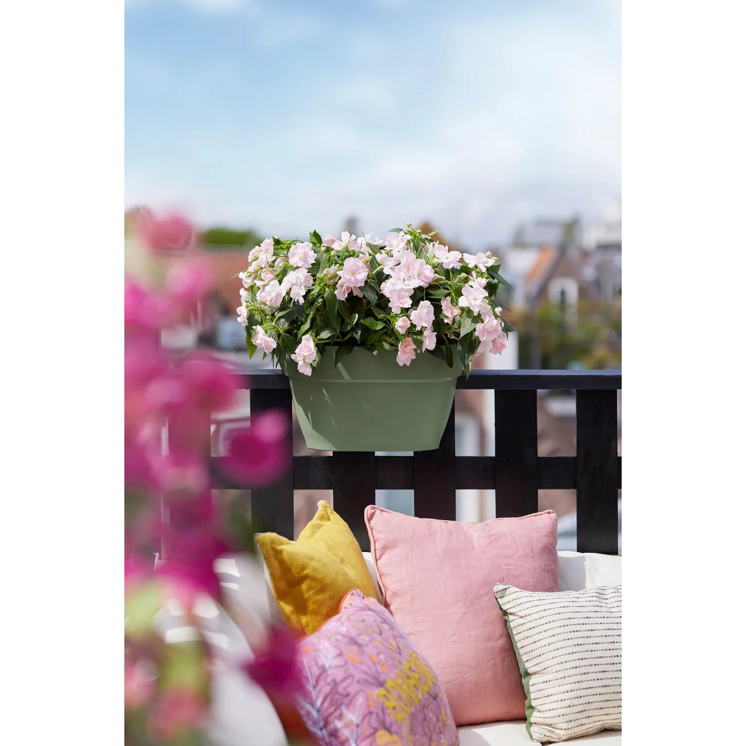 Elho Vibia Campana portafiori antracite con fiori rosa su una ringhiera del balcone.