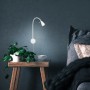 Lampada da comodino a LED Briloner Tusa, orientabile, bianco caldo, montata su parete blu sopra il comodino.