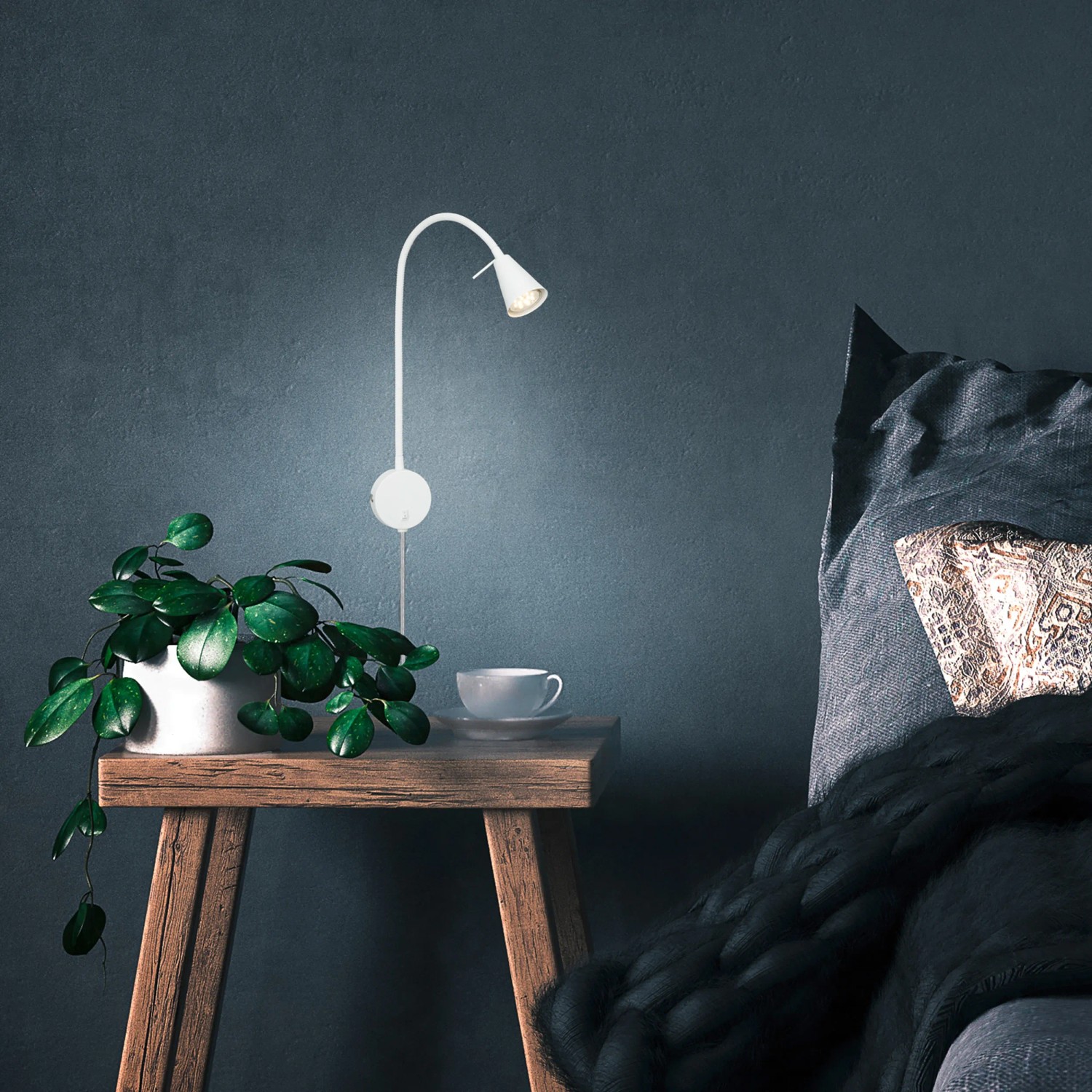 Lampada da comodino a LED Briloner Tusa, orientabile, bianco caldo, montata su parete blu sopra il comodino.