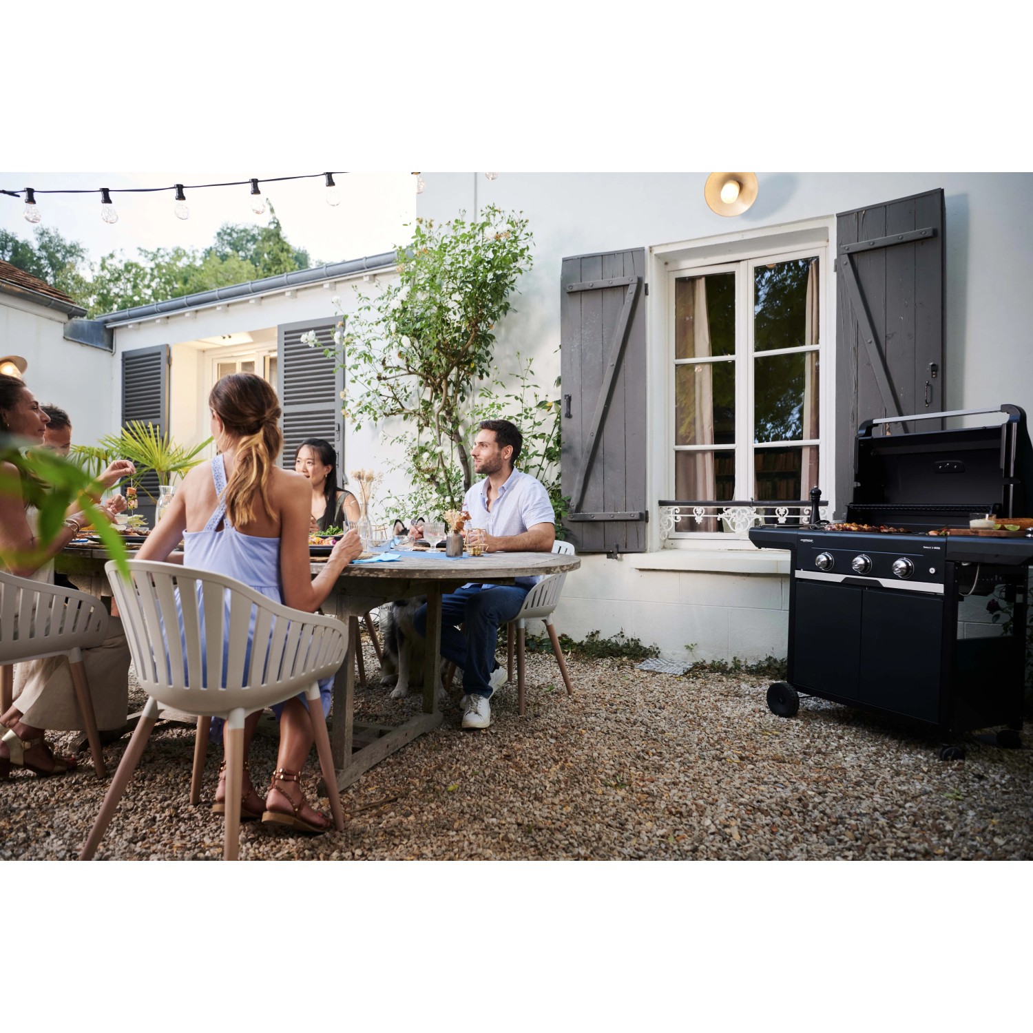 Barbecue a gas nero t.b.t. in giardino con persone che festeggiano.