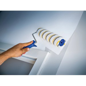 Rullo a dispersione LUX 18cm mentre dipinge una parete. Rullo per pittura con rivestimento in polymix, a righe oro-grigio.