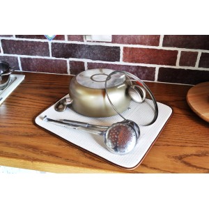 Pentola e mestolo su un sottopentola. Utensili da cucina su un piano di lavoro.