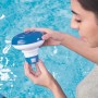 Donna tiene in mano il galleggiante chimico per piscina Bestway per la cura della piscina sull'acqua.