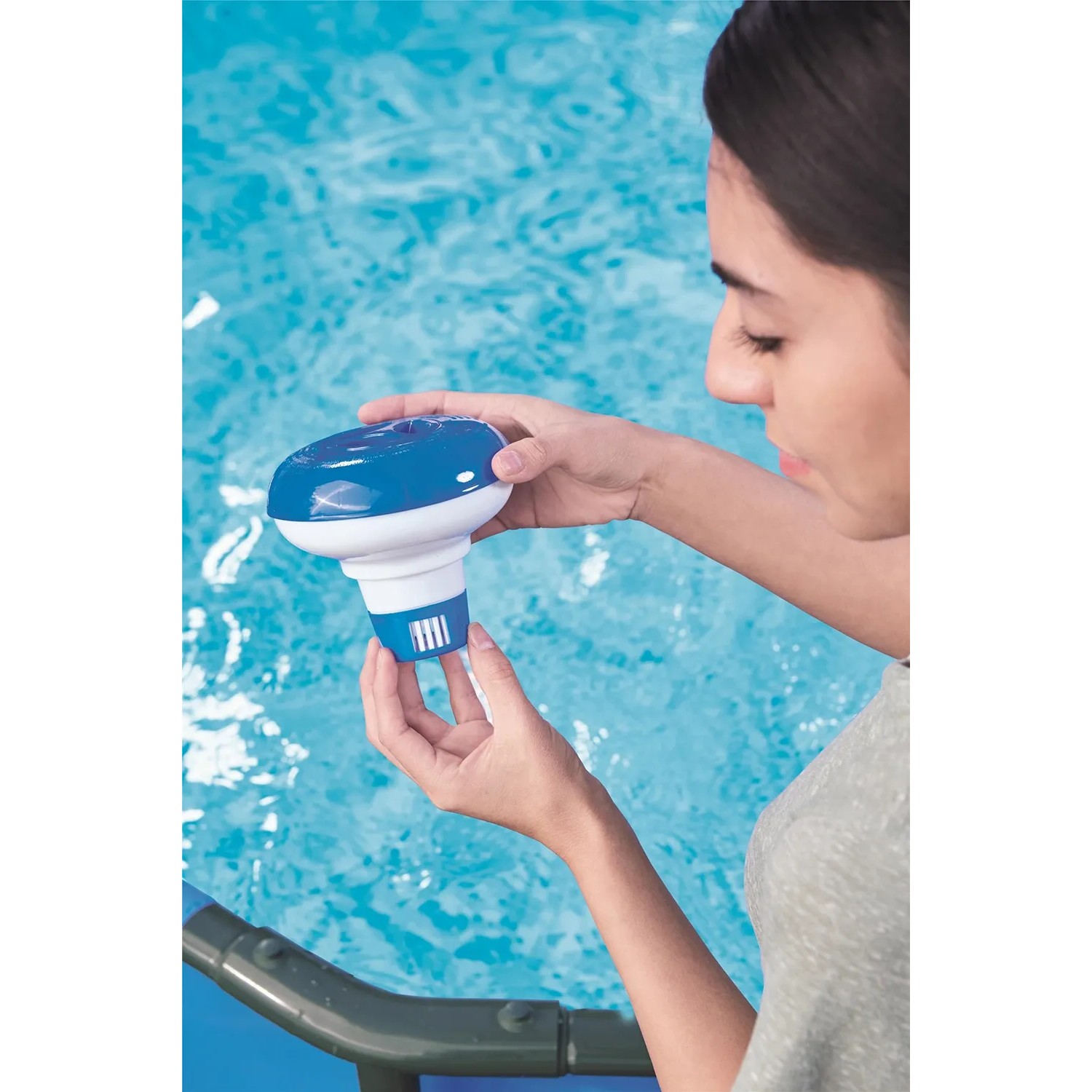 Donna tiene in mano il galleggiante chimico per piscina Bestway per la cura della piscina sull'acqua.