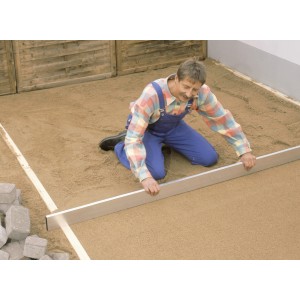 Un uomo livella il massetto con la staggia LUX Classic da 2 m. Utensile da muratore in uso.