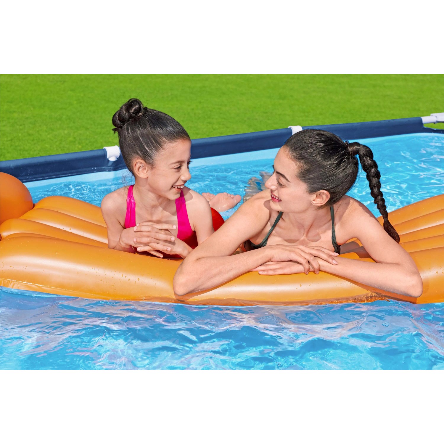 Due ragazze si rilassano su un materassino in piscina. Piscina fuori terra sullo sfondo.