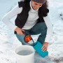 Donna riempie lo spargitore Gardena Kleinstreuer S (turchese) con materiale antighiaccio da un secchio. Spargitore per servizi invernali.
