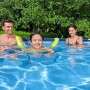 Famiglia che nuota in piscina. Piscina fuori terra per divertirsi in giardino.