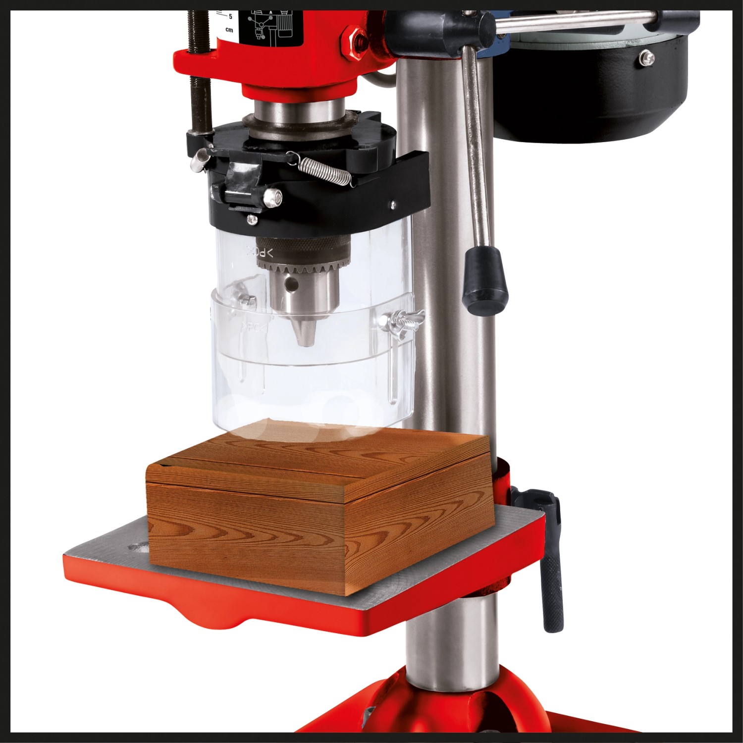 Trapano a colonna Einhell TC-BD 350 che fora un pezzo di legno. Trapano da banco rosso/argento.