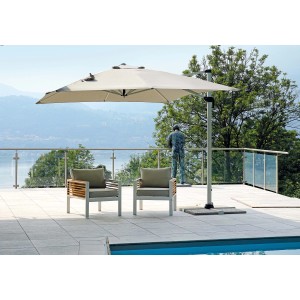 Ombrellone a braccio t.b.t. su terrazza con due poltrone e piscina sullo sfondo.