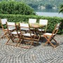 Set tavolo da giardino con tavolo in legno e 6 sedie con rivestimenti bianchi su patio pavimentato.
