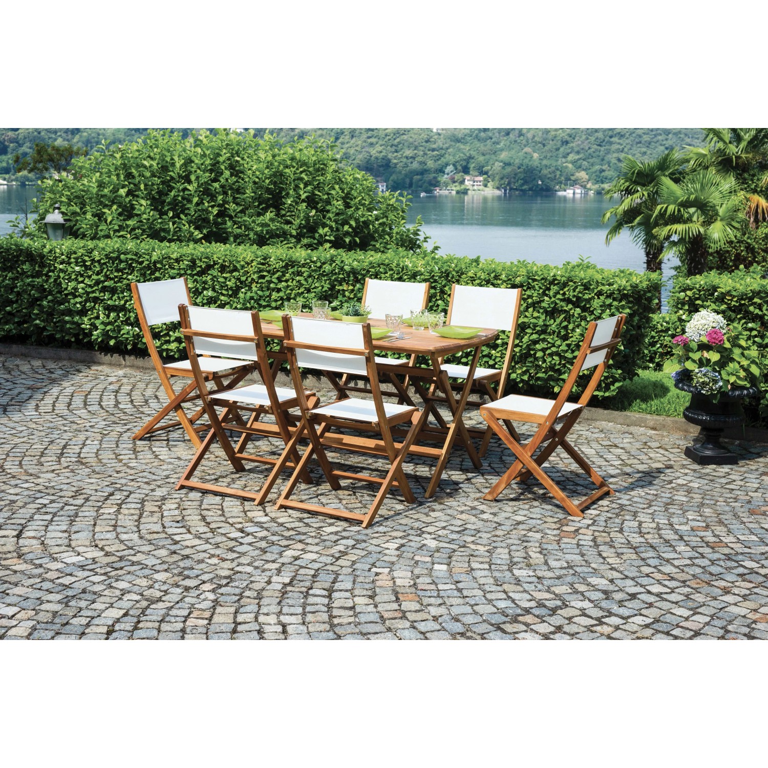 Set tavolo da giardino con tavolo in legno e 6 sedie con rivestimenti bianchi su patio pavimentato.