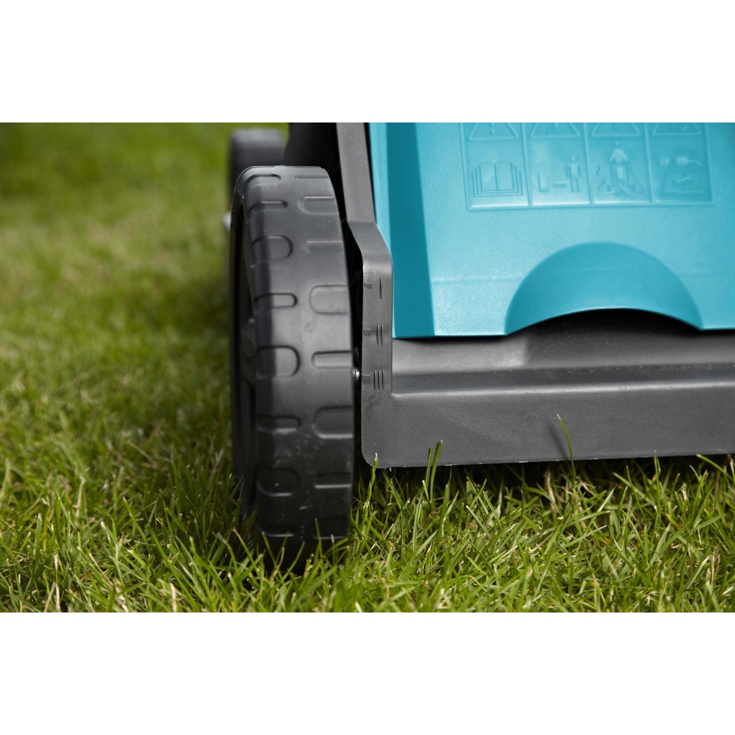 Dettaglio di un tagliaerba elettrico t.b.t. su erba. Focus su ruota e scocca.