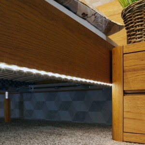 Striscia LED bianca calda montata sotto un letto, che fornisce illuminazione indiretta.