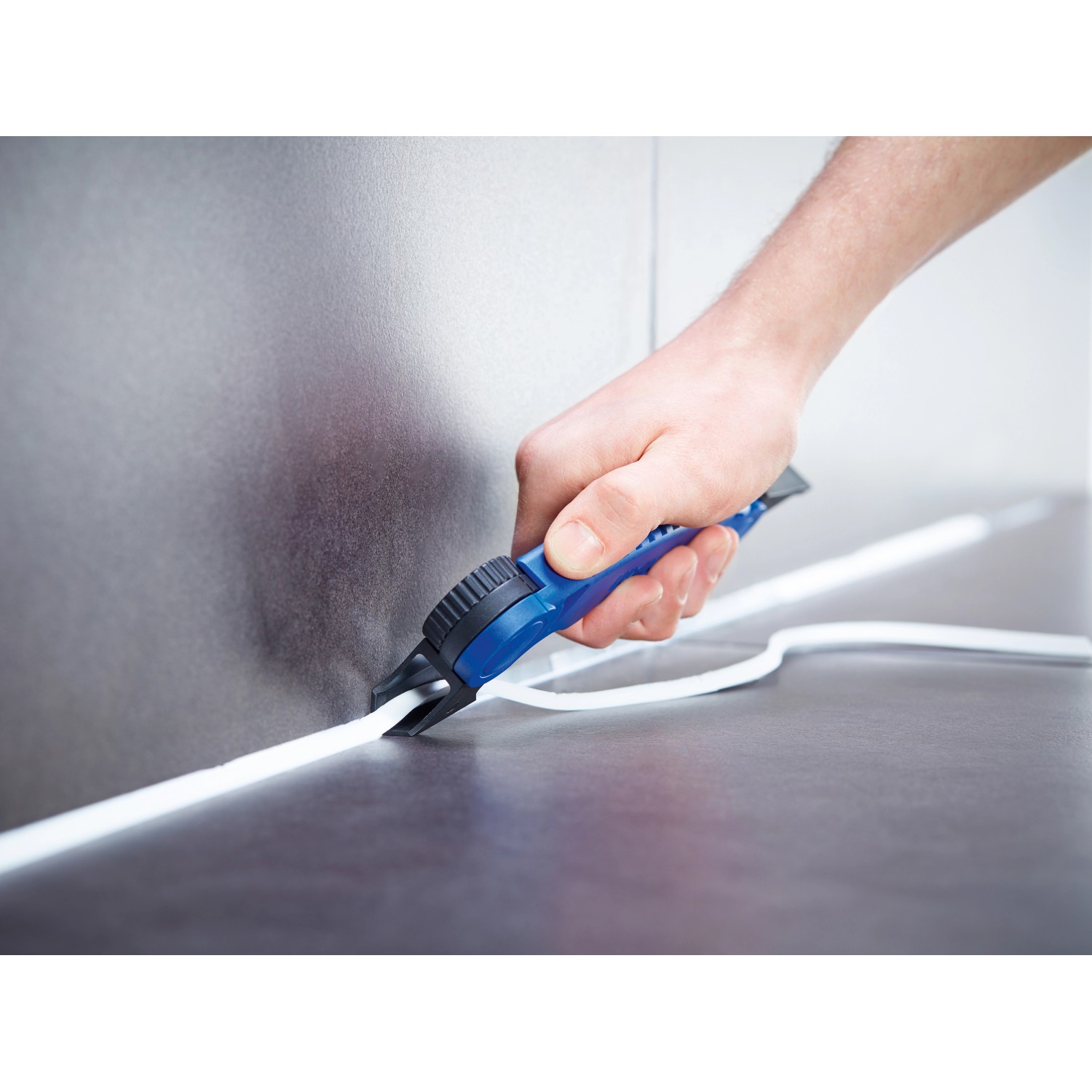 Mano che utilizza il tagliafughe LUX Comfort (6 pezzi) per rimuovere il sigillante siliconico.