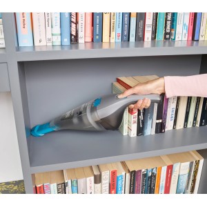 Aspirapolvere portatile a batteria Black+Decker NVC215WA grigio/blu durante la pulizia di una libreria.
