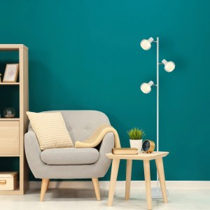 Lampada da terra moderna con tre luci accanto a poltrona e tavolino. Piantane per zona giorno.