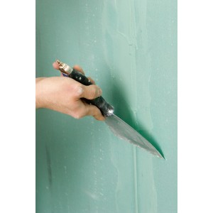 Mano che applica lo stucco per giunti Knauf Uniflott su una parete in cartongesso verde. Accessori per cartongesso.