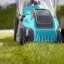 Tagliaerba elettrico turchese e grigio su prato. Tagliaerba compatto.