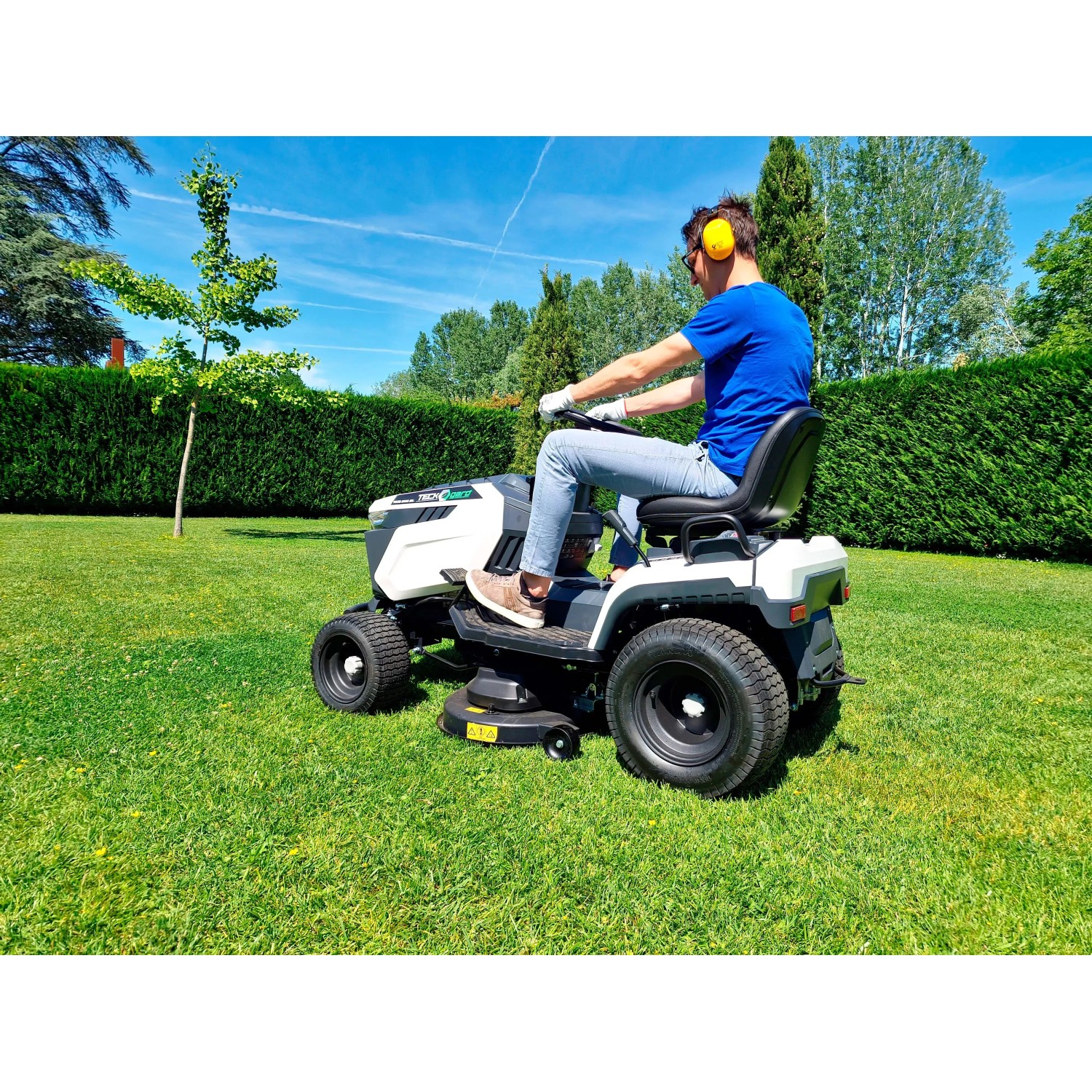 Trattorino tagliaerba mentre taglia l'erba in giardino. Il trattore è bianco e nero.