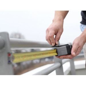 Mano che misura una ringhiera grigia con il metro a nastro LUX Professional da 10 m.