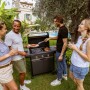 Gruppo di amici che grigliano con un barbecue a gas. Barbecue in giardino.