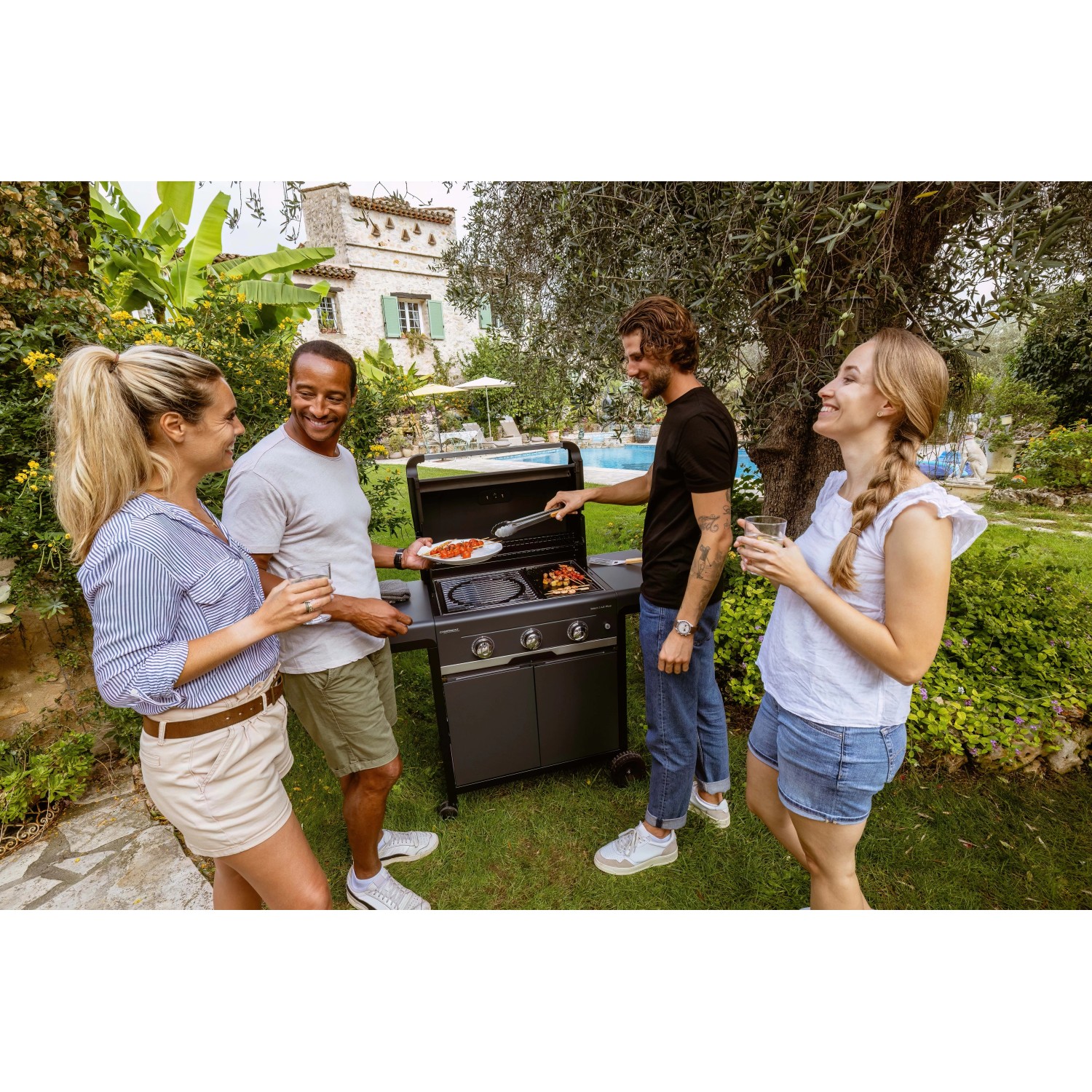 Gruppo di amici che grigliano con un barbecue a gas. Barbecue in giardino.