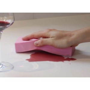Spugna rosa che pulisce vino rosso su una superficie chiara. Strumento per la pulizia.