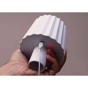 Lampada decorativa da esterno t.b.t. bianca con cavo di ricarica USB tenuta in mano.