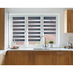 Tenda a rullo t.b.t. grigia e bianca su una finestra in cucina.