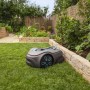 Robot tagliaerba t.b.t. grigio con dettagli blu su prato in giardino.