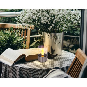 Lampada da tavolo solare a LED Globo con effetto fuoco in acciaio inox su tavolo con libro e vaso di fiori.